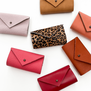 A group of seven needle cases of various colours are displayed on a white top.